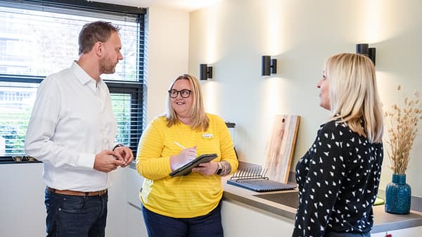 Un collaborateur IKEA en chemise jaune aidant deux clients chez eux.