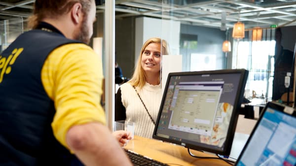 Un collaborateur IKEA qui répond à une cliente à un comptoir de service IKEA.