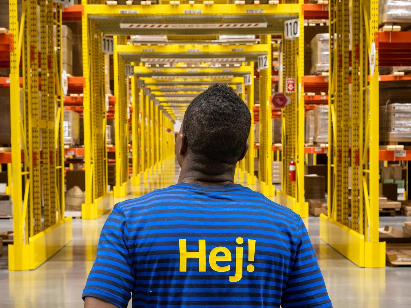 Un collaborateur IKEA se tient dans un centre de distribution clients et observe les rayonnages de l’entrepôt.