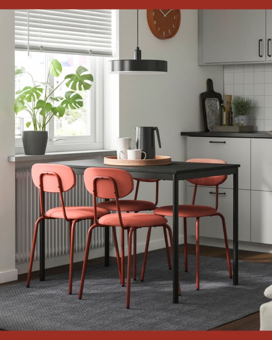 Un comedor con mesa rectángular y cuatro sillas de comedor rojas.