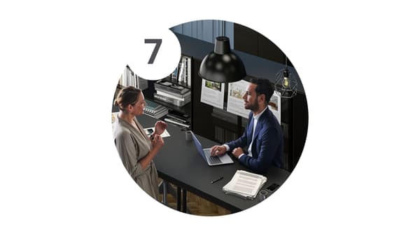 Un consulente che sta ascoltando le richieste di una cliente in un ufficio con mobili scuri