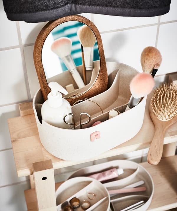 Un contenitore SAXBORGA aperto con all'interno diversi strumenti e oggetti per il make up, posto sopra uno scaffae scaffale VILTO.