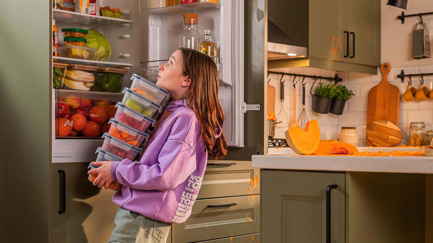 Un copil duce recipiente cu mâncare la frigider