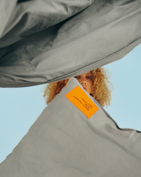 Un copripiumino grigio e un set di federe con un’etichetta arancione - IKEA