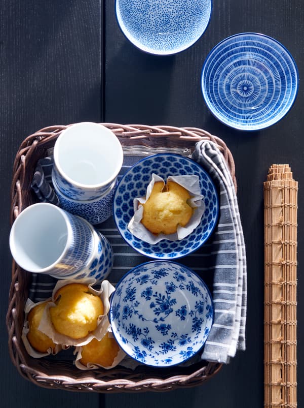 Un coș GABBIG lângă care este aliniat un șervet TIMVISARE și care este plin cu căni ENTUSIASM și brioșe proaspăt coapte.