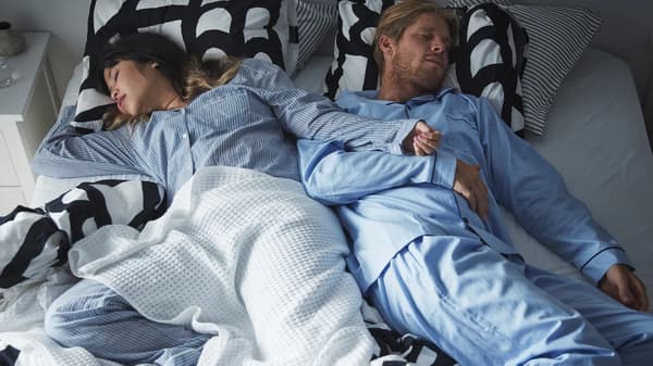Un couple profondément endormi et portant le même pyjama est étendu sur un lit double.