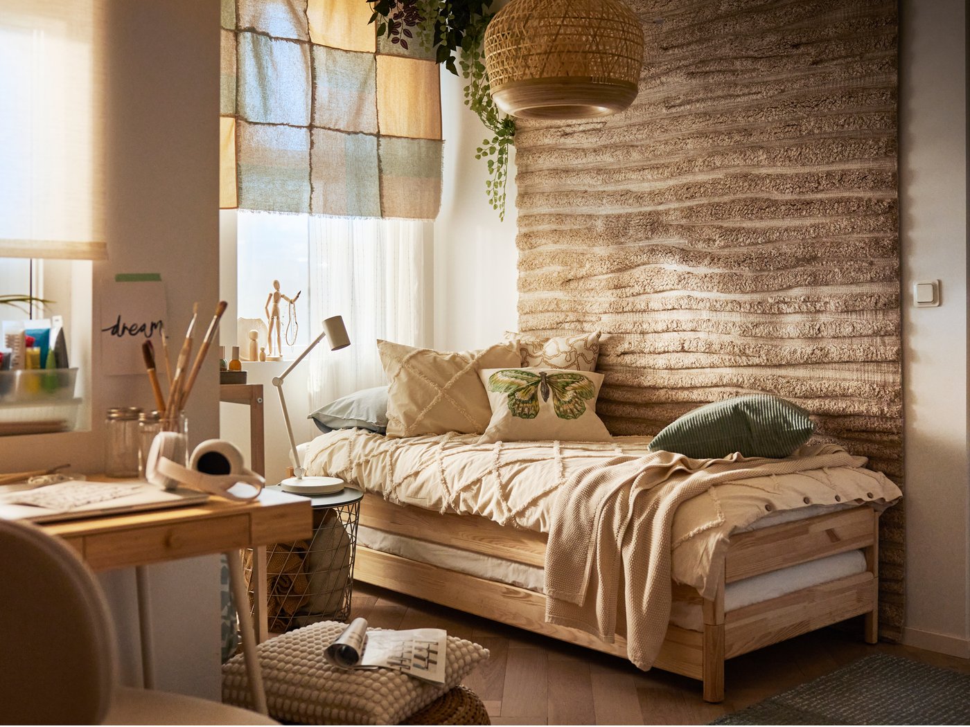 Un cuarto de estilo rústico cunha cama amontoable UTÅKER de piñeiro vestida con roupa de cama NYPONLUGGMAL xunto a unha parede e cunha alfombra con textura enriba.