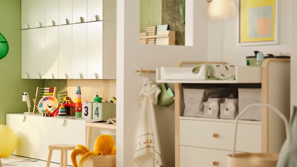 Un cuarto infantil parcialmente separado por unha parede. Hai armarios SMÅSTAD e xoguetes nun lado. No outro, hai unha zona cun cambiador.
