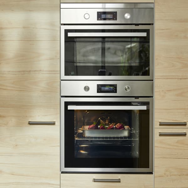 Un cuptor mai mare și unul mai mic în combinația negru/oțel inoxidabil și fronturi de sertare și de uși cu efecte de striații subtile.