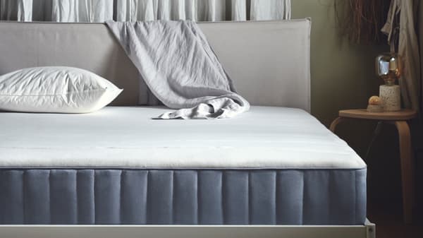 Un cuscino LAPPTÅTEL e un materasso a molle insacchettate VESTERÖY rigido/azzurro su una struttura letto.