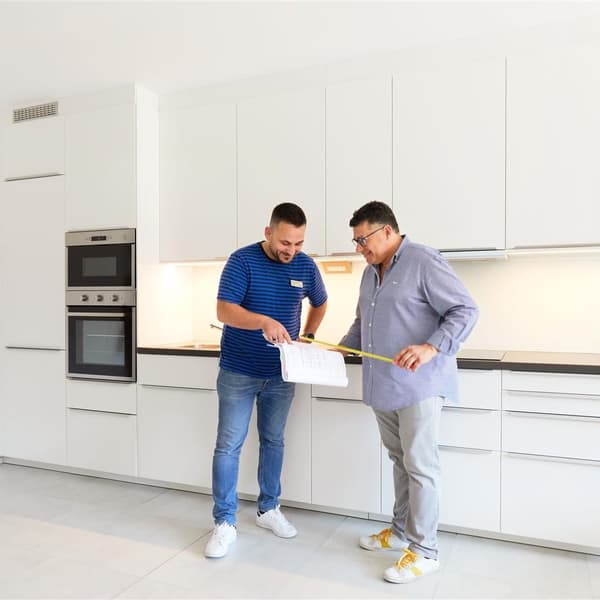 Un dipendente IKEA mostra a un cliente un disegno di progetto per una nuova cucina in un complesso residenziale.