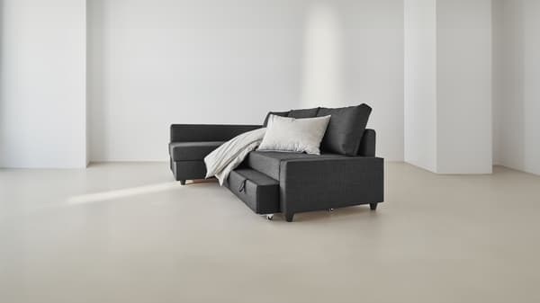 Un divano angolari di colore grigio con cuscini in una stanza vuota bianca e beige.