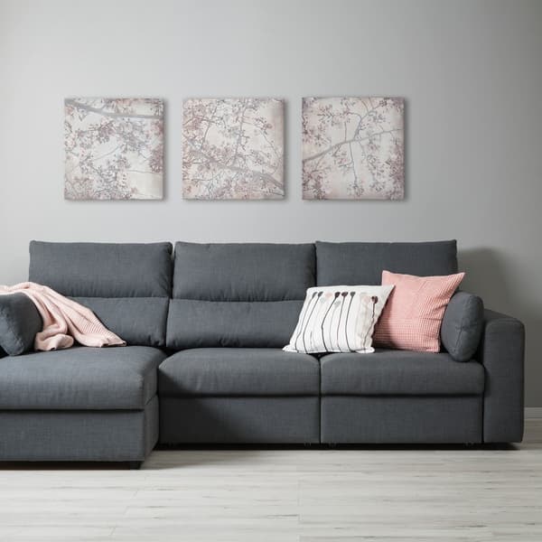 Un Divano ESKILSTUNA grigio scuro con cuscini e plaid all'interno di una stanza. Nella stanza sono appesi alle parete 3 quadri con decorazioni floreali - IKEA