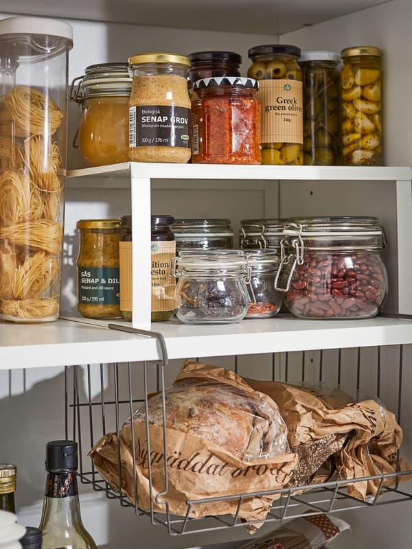 Un divisorio per ripiano in acciaio laccato bianco e un cestino pensile all’interno di un ripiano della dispensa adibito alle marmellate, ai barattoli e alle bottiglie - IKEA