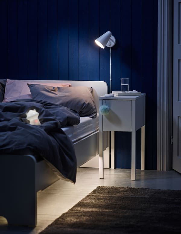 Un dormitori infantil amb un llum de paret IKEA FUBBLA de color blanc.