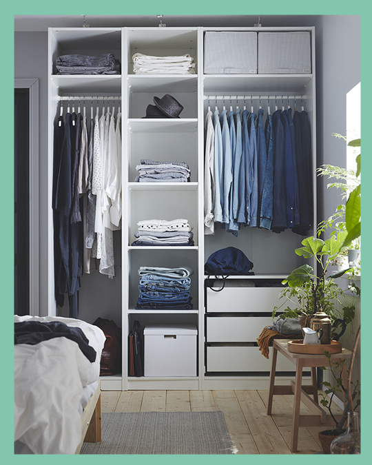 Un dormitorio con un clóset grande con sus repisas organizadas con cajas y en la  barra ropa colgada.