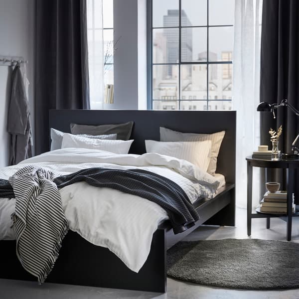 Un dormitorio en blanco, negro y gris, que recuerda a una suite de hotel.