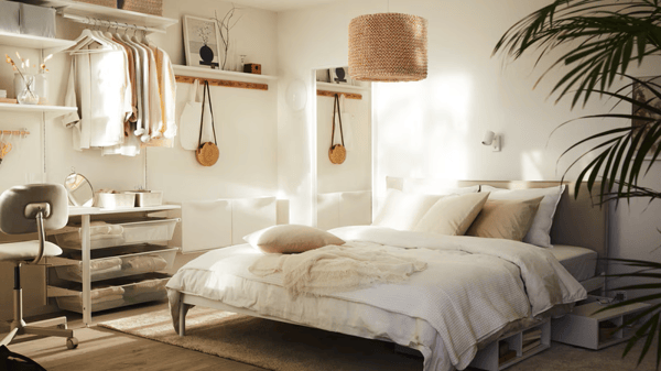 Un dormitorio soleado con una cama KLEPPSTAD con ropa de cama blanca ÄNGSLILJA y una lámpara LERGRYN colgada encima.