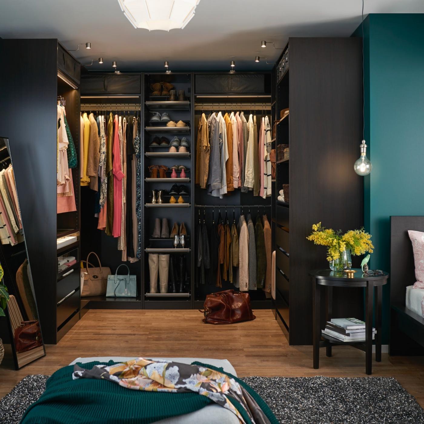 Un dressing PAX din lemn de culoare închisă, amplasat într-o cameră văruită în albastru-turcoaz. O cuvertură decorativă turcoaz este așezată pe un pouf.