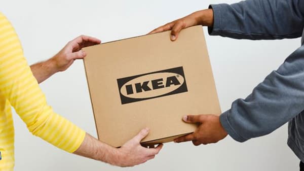 Un employé d'IKEA remet un colis IKEA à une personne.