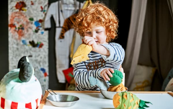 Un enfant joue avec des peluches à table.