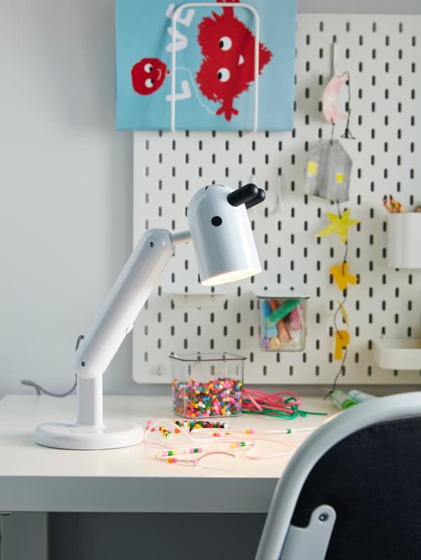Un escritorio con una lámpara KRUX de IKEA, que tiene forma de cabeza de animal con orejas y nariz, en blanco y negro, de IKEA.