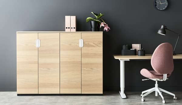 Un escritorio y una silla de oficina al lado de un mueble alto de color madera.