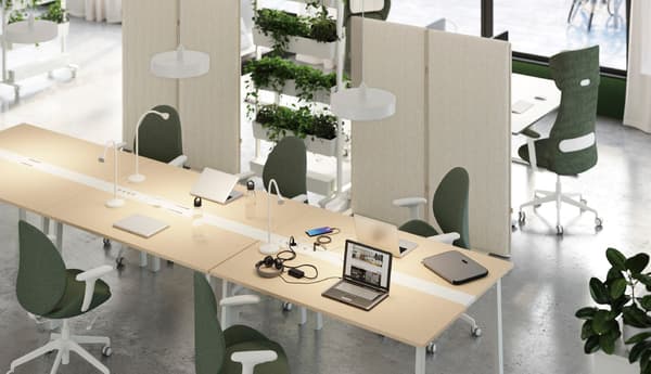 Un espace de bureau moderne présente plusieurs bureaux avec des chaises vertes, des lampes blanches, un ordinateur portable, un casque, des carnets, des stylos et des plantes en arrière-plan.