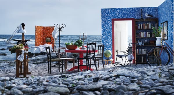 Un espacio de hogar instalado a la orilla de una playa con muebles clásicos y paredes en sintonía al fondo marino. 