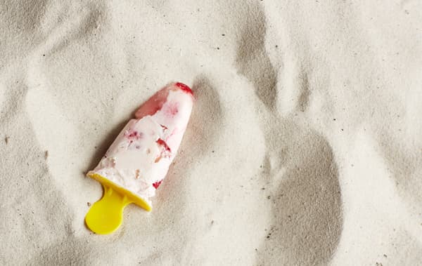 Un esquimau au yaourt à la framboise posé sur le sable