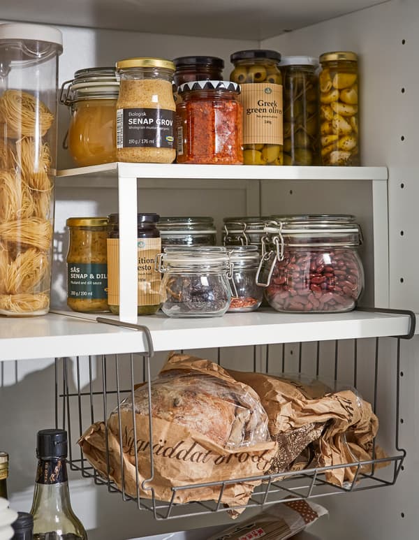 Un estante adicional IKEA VARIERA branco e unha cesta colgante OBSERVATÖR para crear espazo para almacenar marmeladas, tarros e botellas.
