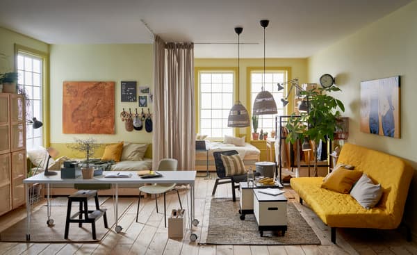 Un estudio con dos camas individuales separadas del espacio del salón por unas cortinas con muebles de IKEA.