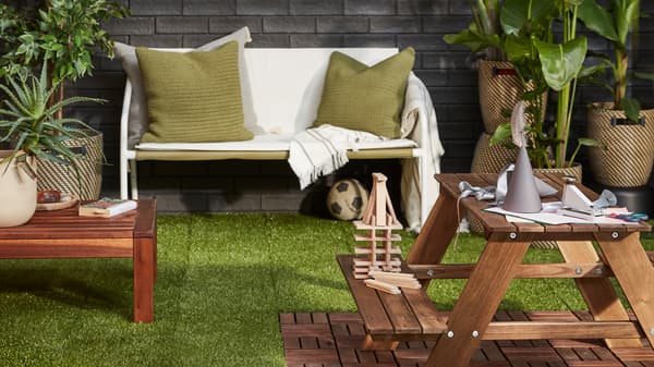 un extérieur avec du gazon synthétique et des meubles de jardin en bois