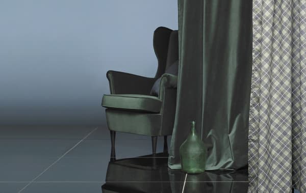Un fauteuil derrière un rideau en velours vert foncé.