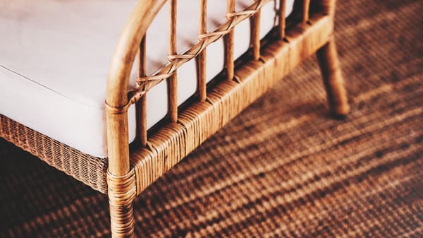 Un fauteuil HOLMSTA/FRÖKNABO en bois et rotin avec coussins, sur un tapis tissé à plat LOHALS.