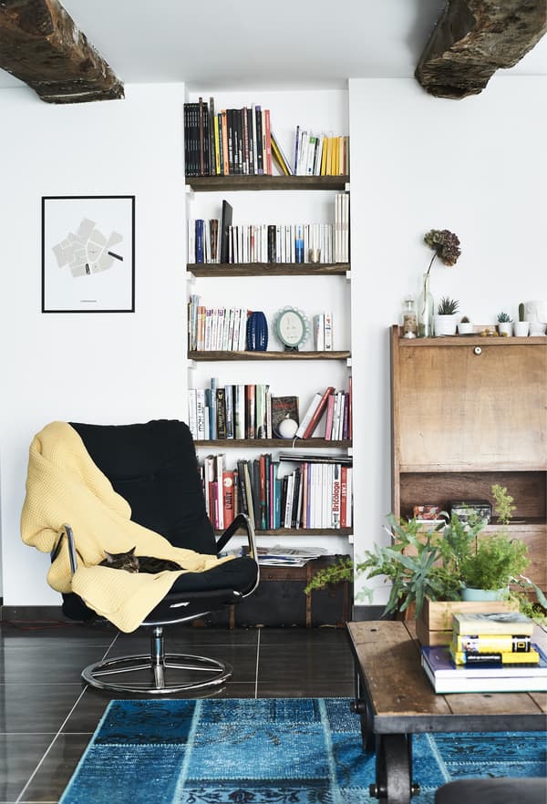 Un fauteuil pivotant IKEA noir vintage, avec plaid jaune.