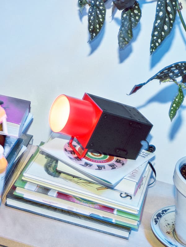 Un foco de luz IKEA FREKVENS de cor vermella e negra sobre un montón de libros.