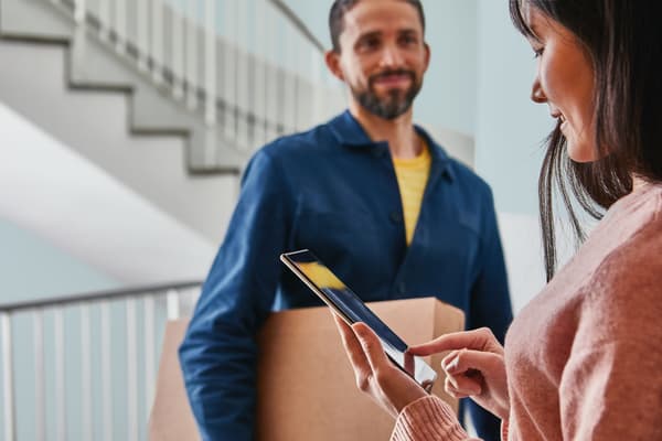 Un fornitore consegna un pacco a una cliente sulla porta di casa