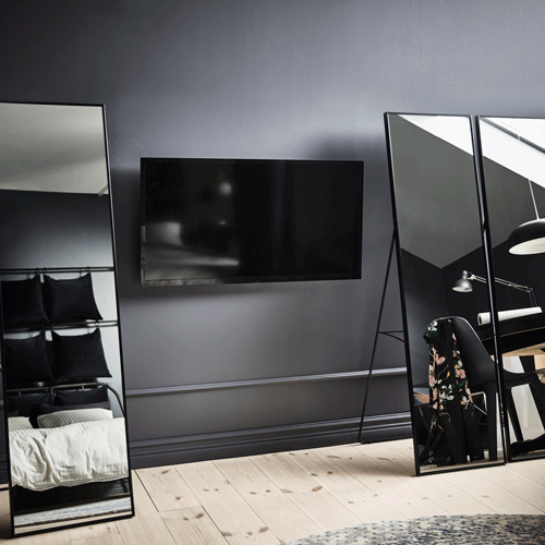 Un GIF de tres miralls de peu IKEA KARMSUND que es mouen per descobrir una TV penjada a la paret d’un dormitori.