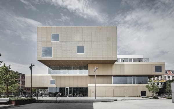 Un grand bâtiment en forme de blocs empilés, avec un habillage en métal doré.