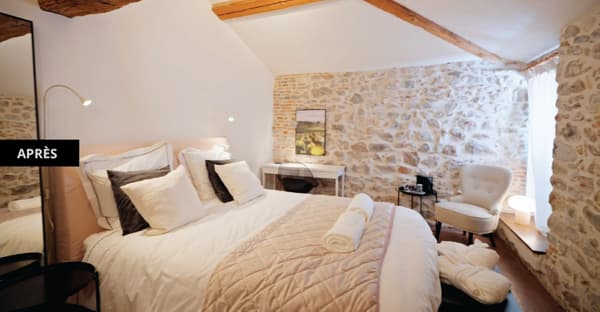 Un grand lit avec une couette blanche, plusieurs coussins et deux serviettes roulées dessus.