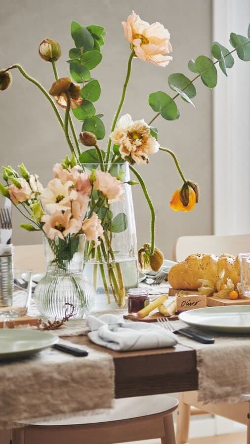 Un gros plan sur le plateau d'une table sur lequel se trouvent des assiettes et plusieurs petites bouteilles de sirop, à côté d'un vase avec des fleurs.
