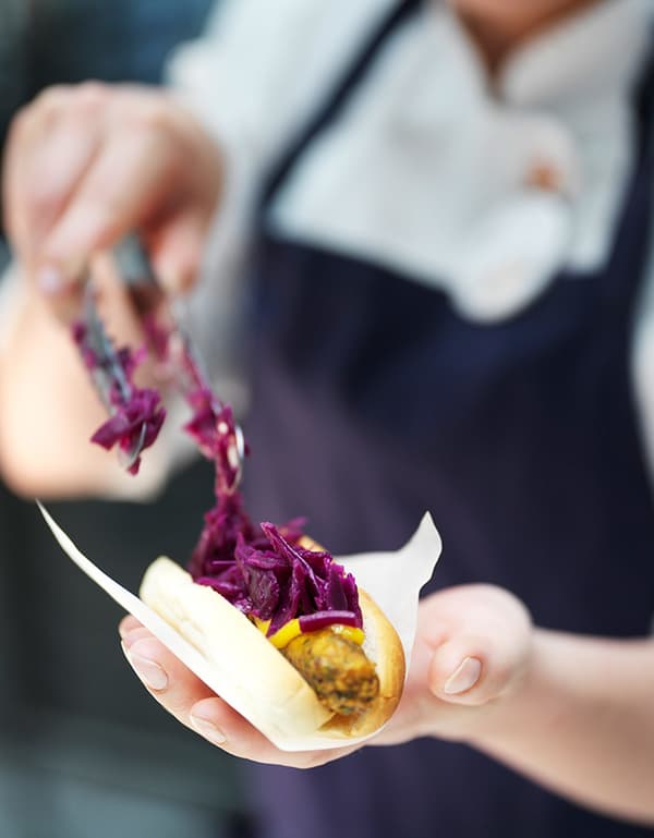 Un gros plan sur un hot-dog végétarien IKEA à base de plantes servi avec du pain, de la moutarde et du chou rouge.