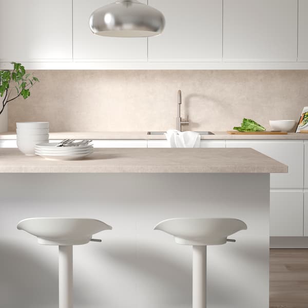 Un gros plan sur un îlot de cuisine avec 2 tabourets de bar et une kitchenette IKEA derrière.