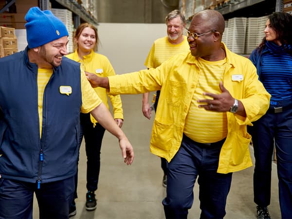 Un groupe diversifié de collaborateurs IKEA qui traversent le rayon libre-service d’un magasin IKEA.