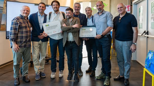 Un gruppo di persone mostra la targa che certifica che nel condominio l'energia elettrica è prodotta da pannelli fotovoltaici. 