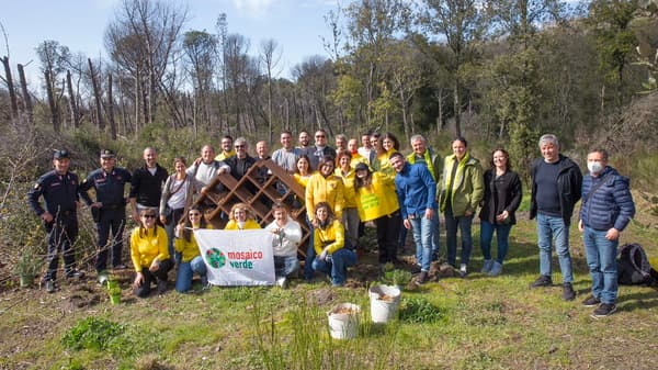 Un gruppo di persone posa davanti a una bee-house appena finita. 