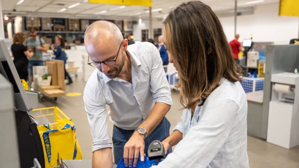 Un hombre y una mujer en una caja autoservicio comprando productos IKEA.