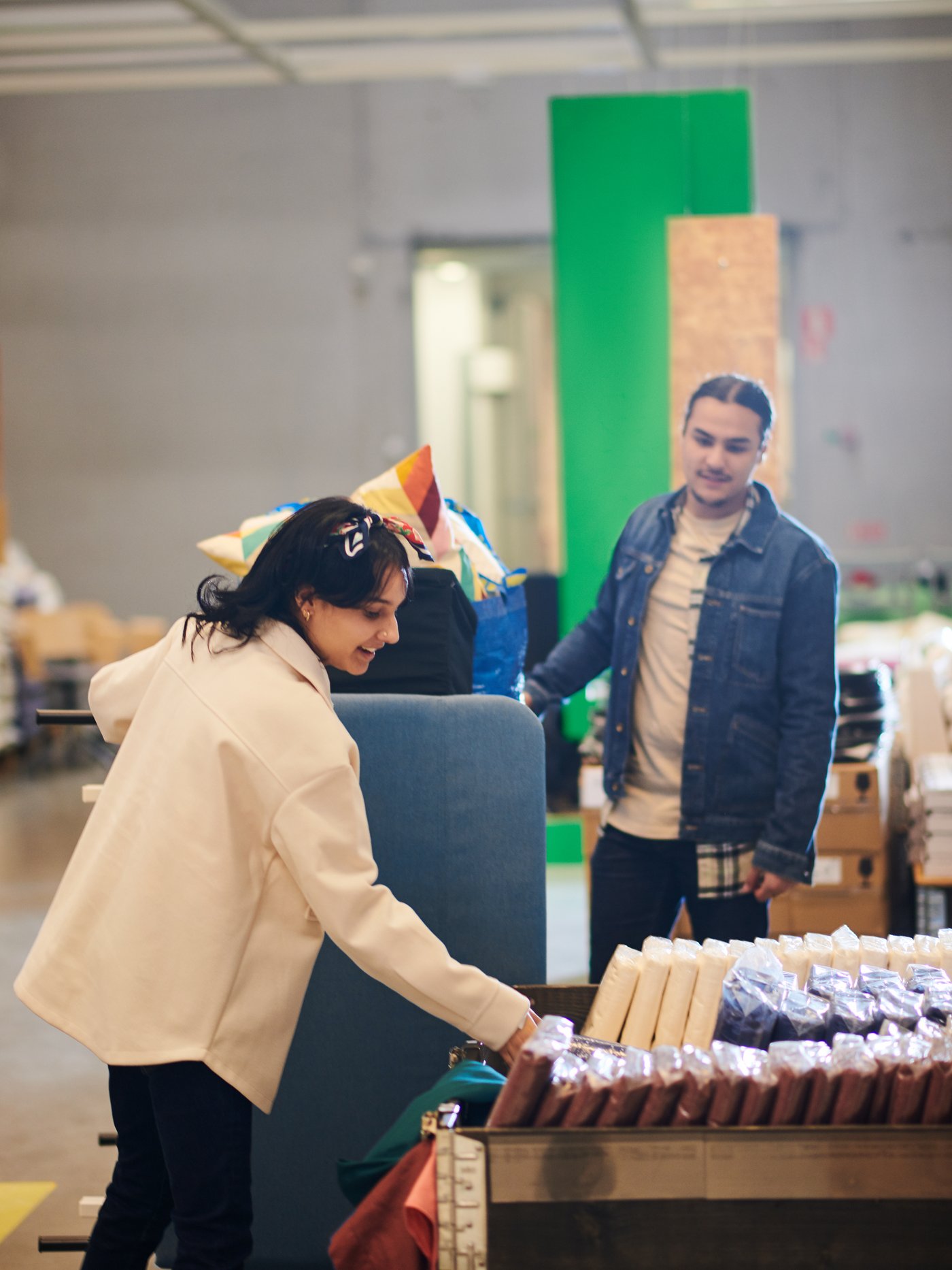 Un home i una dona a la secció d'ofertes per temps limitat i d'ocasió d'IKEA que trien roba de llit en un aparador de productes.