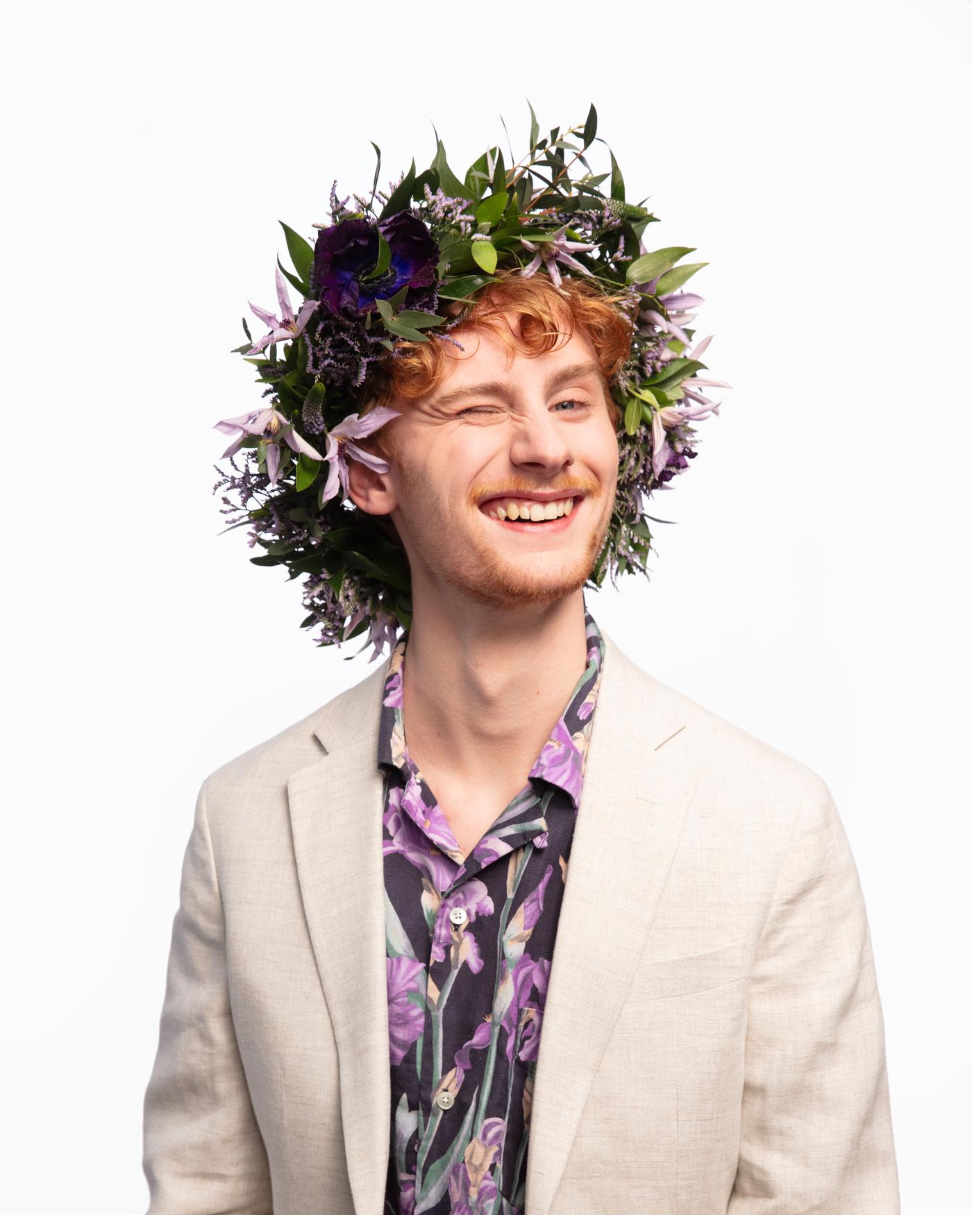 Un home sorrindo cunha coroa de flores